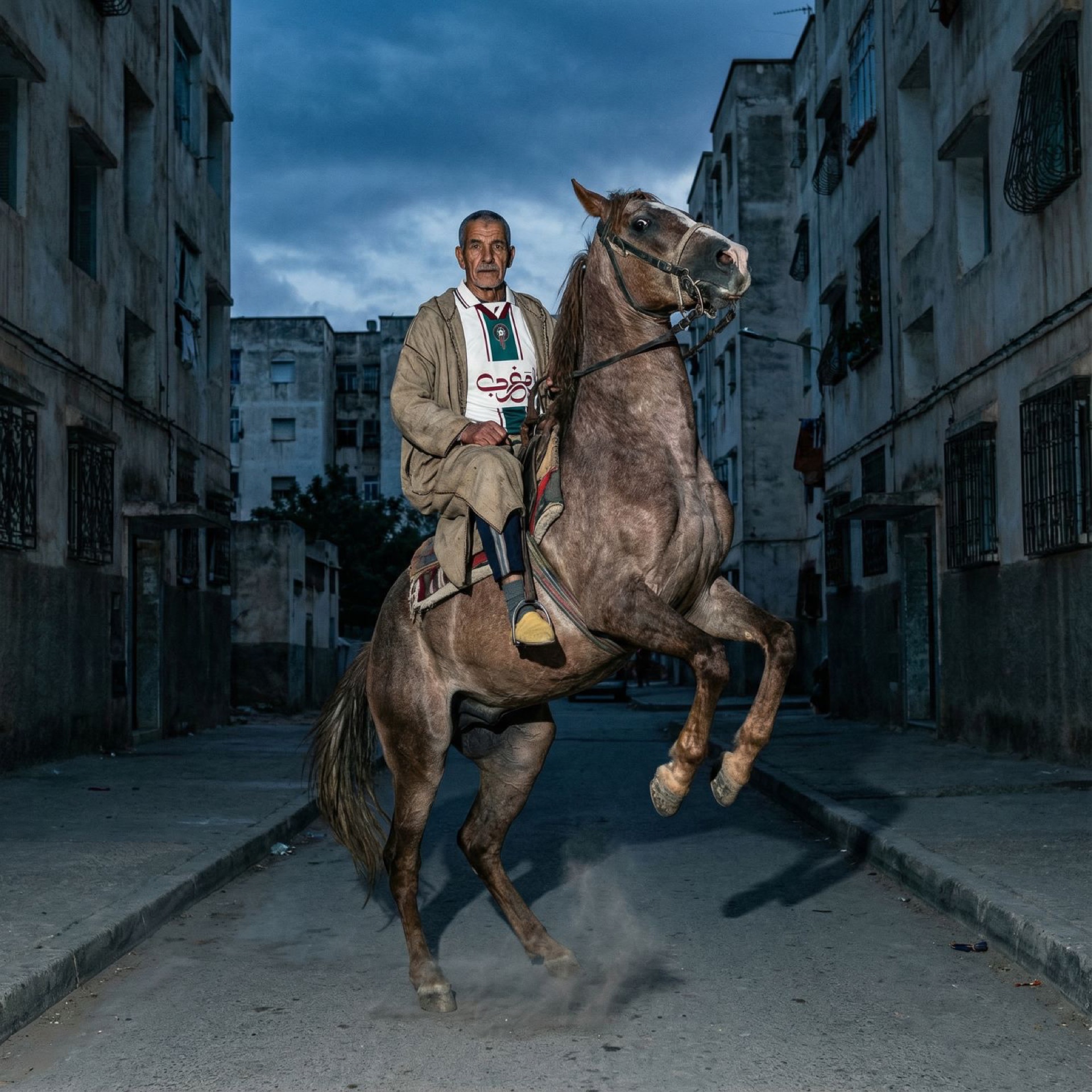 Man on rearing horse in Moroccan street at dusk
